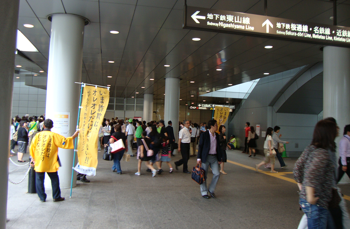 「投資詐欺撲滅キャンペーン」の一環として名古屋駅でビラ配りをしている写真です。